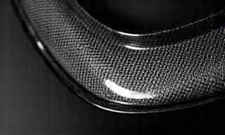 Close-up of a carbon fiber aerodynamic body kit part with intricate weave.