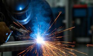 Custom fabricated stainless steel exhaust system being welded in a workshop.